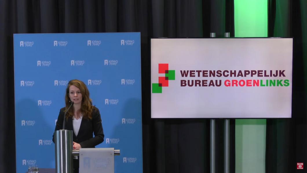 Noortje Thijssen naast een scherm waarop staat 'Wetenschappelijk Bureau GroenLinks'