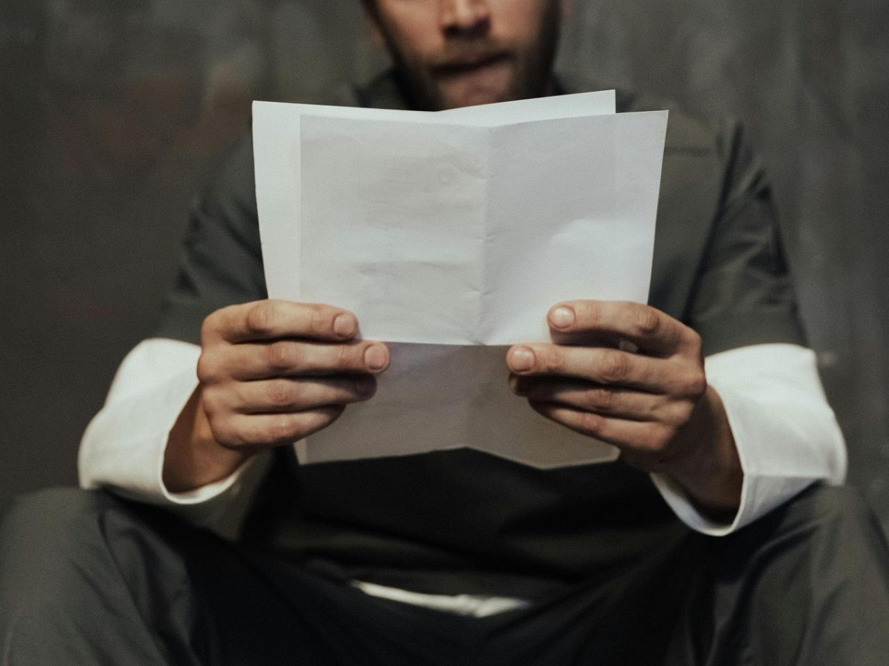 Een persoon houdt een brief in de handen om te lezen.