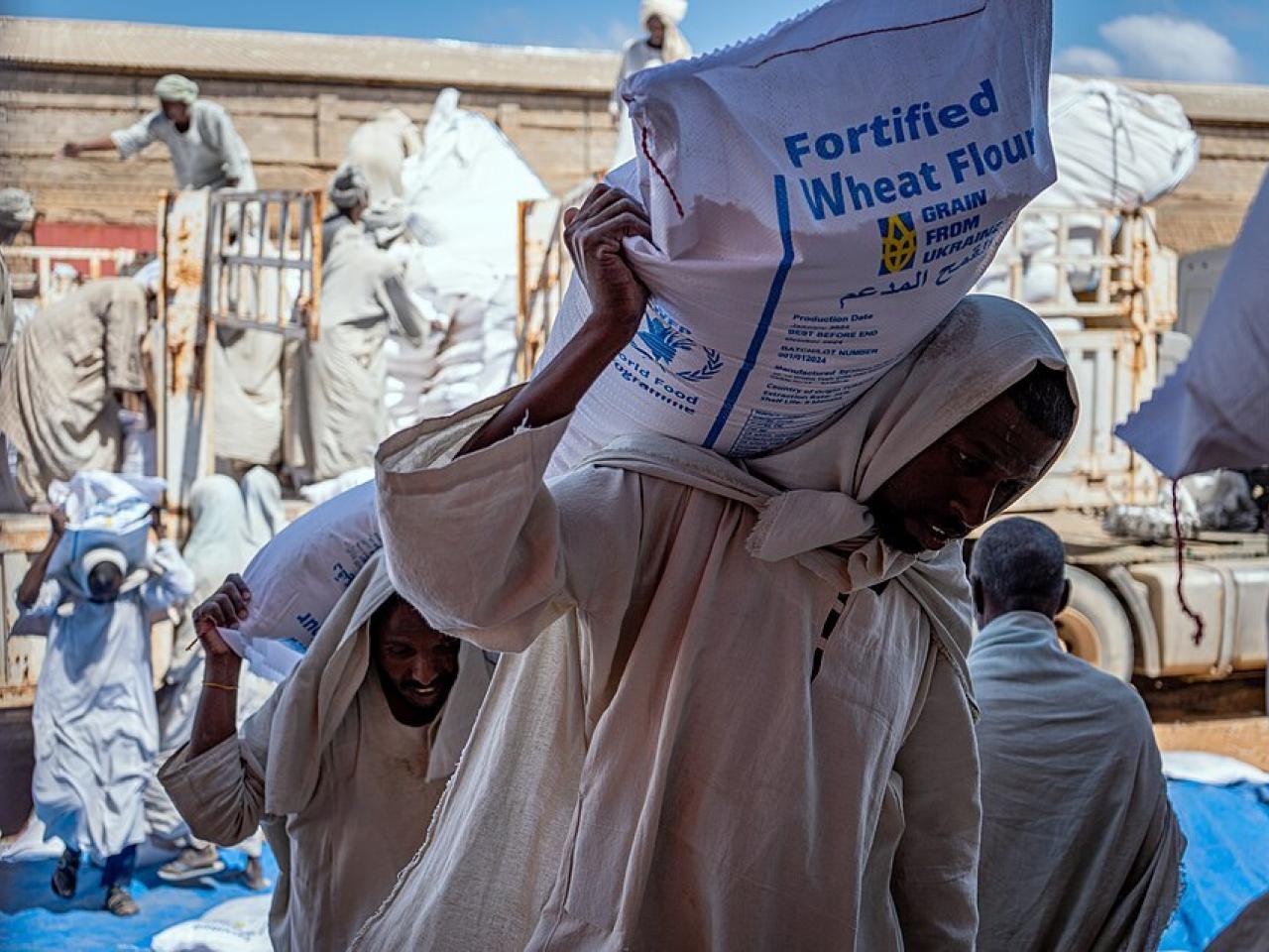 Mensen dragen zakken met graan uit Oekraïne.